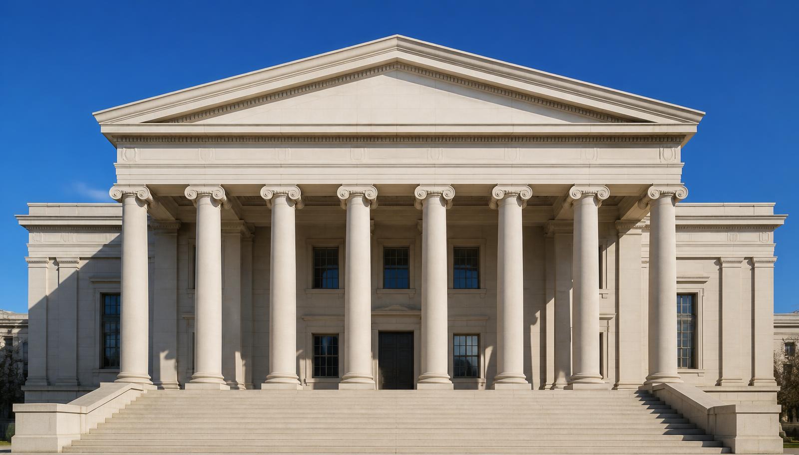 Neoclassical government building with stone columns and wide steps under a clear sky